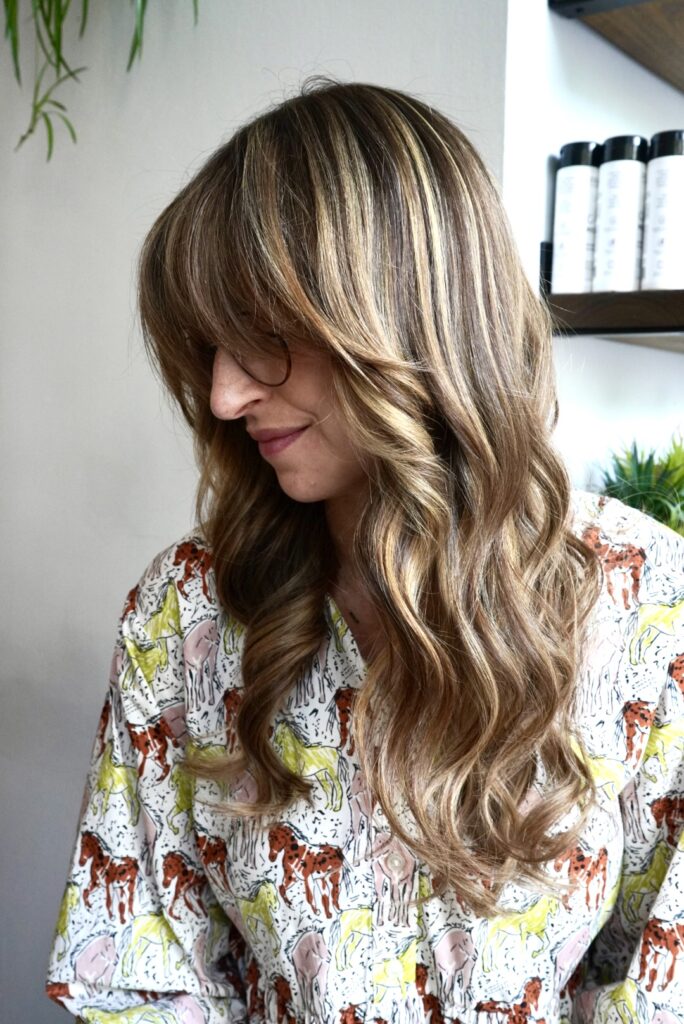 Woman with wavy hair and animal print shirt looking down.