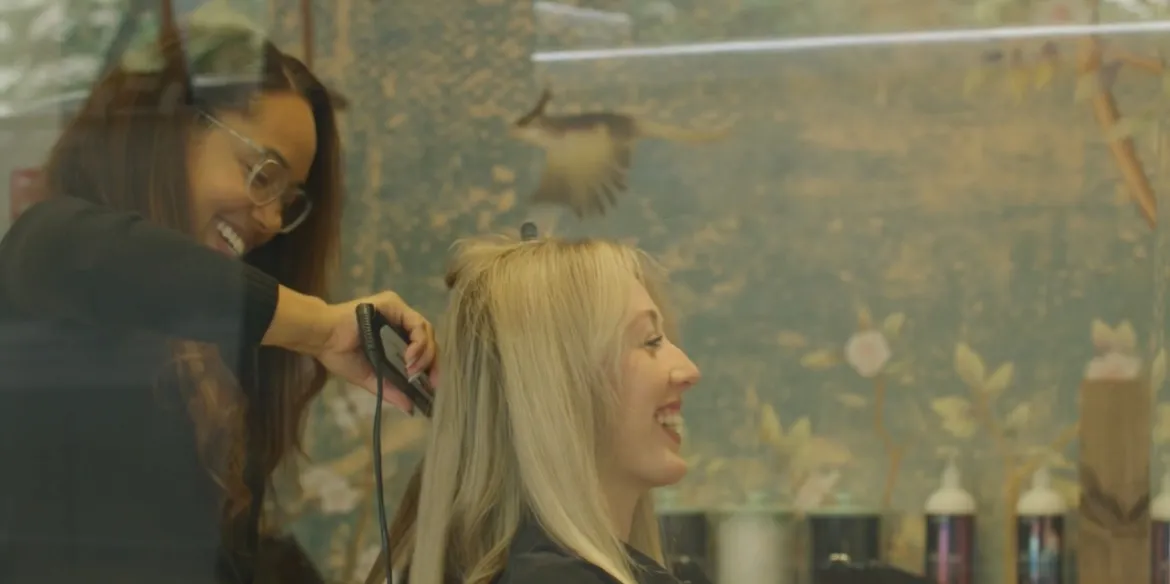 A stylist working on a smiling client's hair at Hair Art Designs.