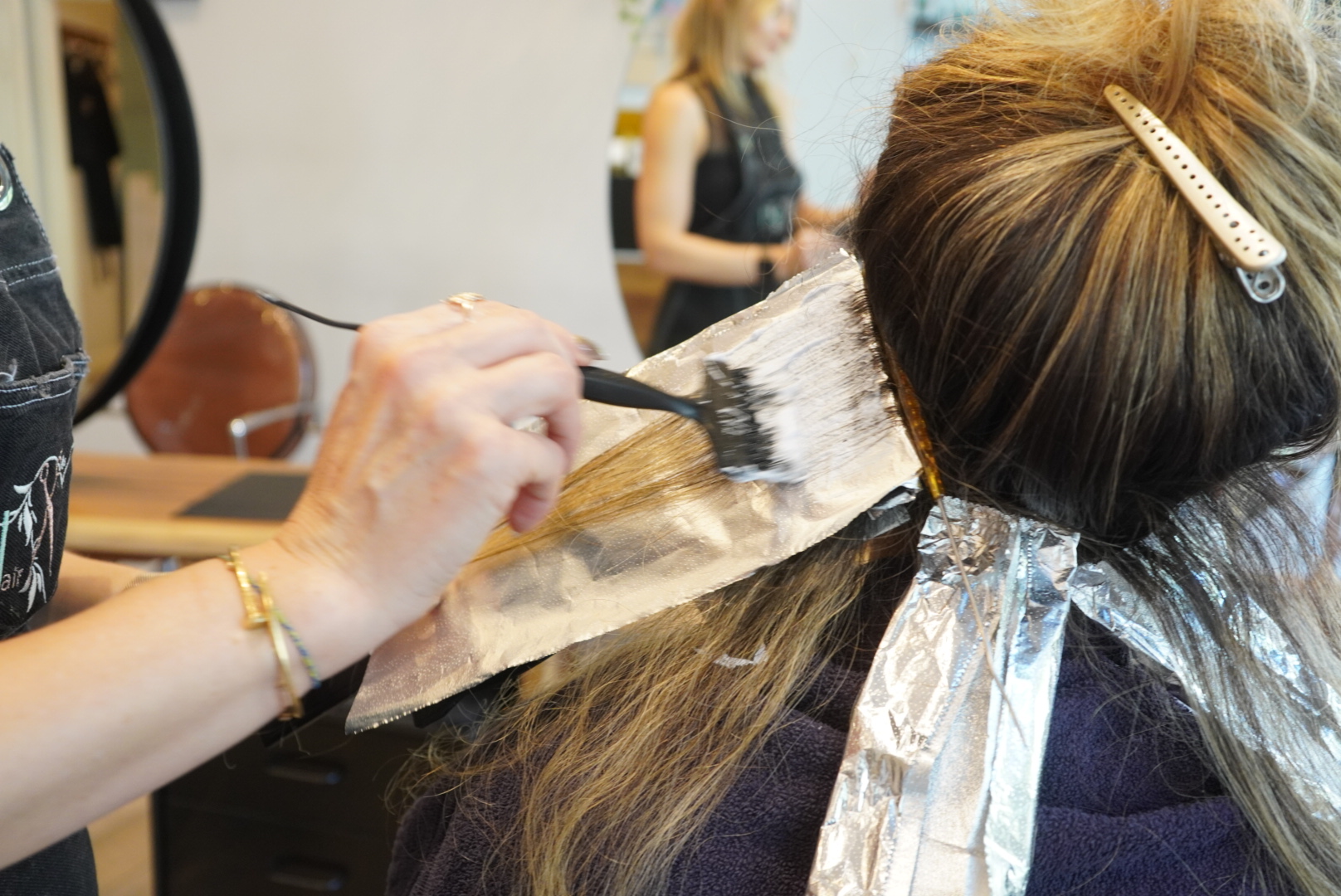 Hairdresser applying hair dye to a woman's hair with foil.