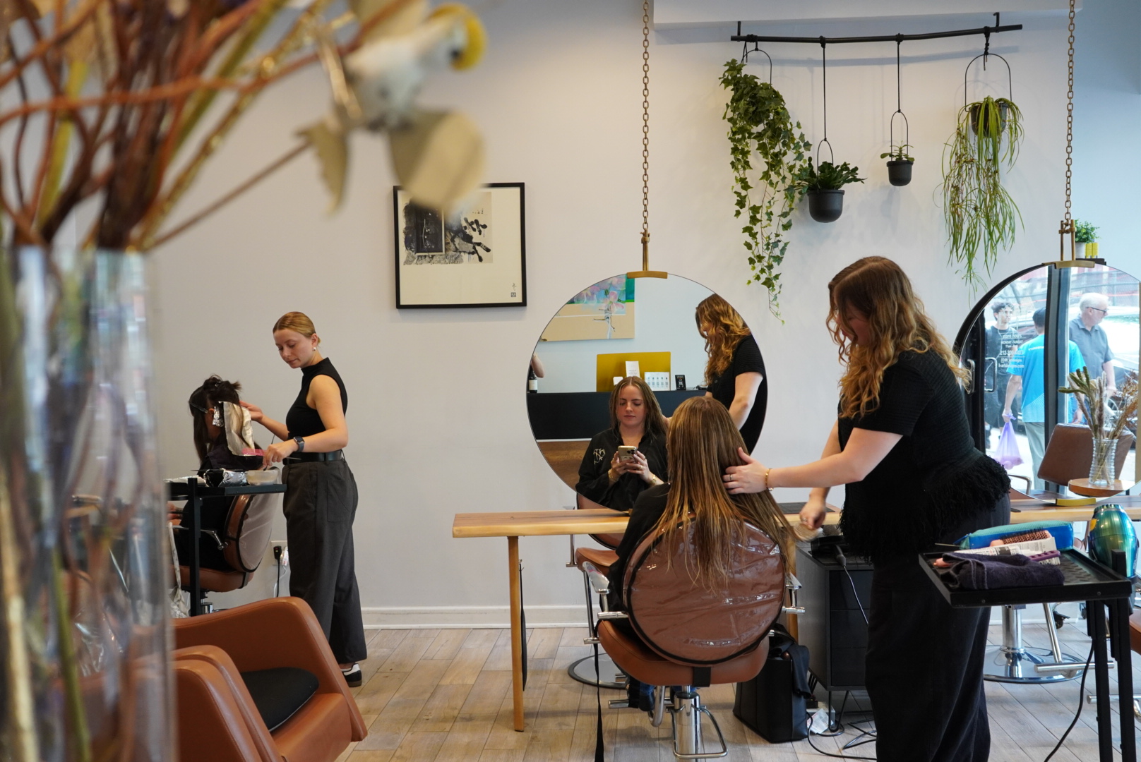 Hair salon with stylists working on clients' hair near round mirrors.