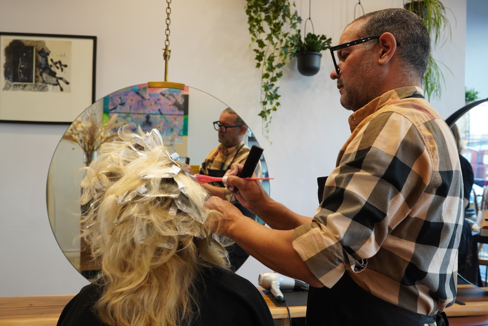 Hairdresser applying color to a client's hair in a salon.