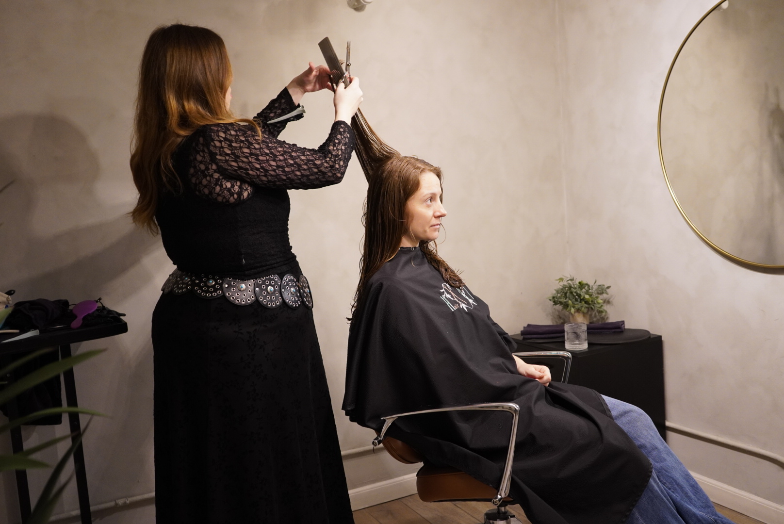 Hairdresser cutting a woman's wet hair in a modern salon setting.