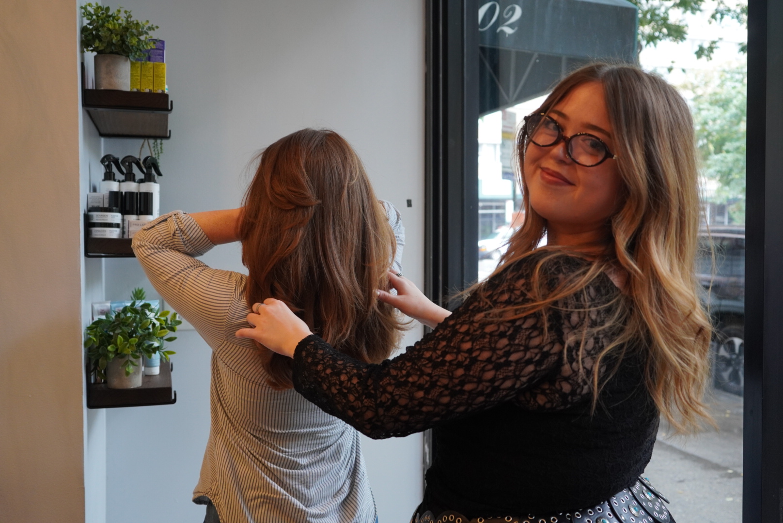 Hair stylist adjusting a client's hair in a salon.