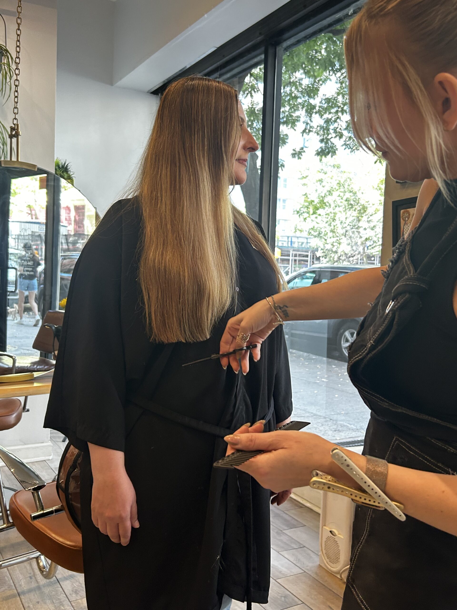 Person with long hair getting a haircut in a salon.