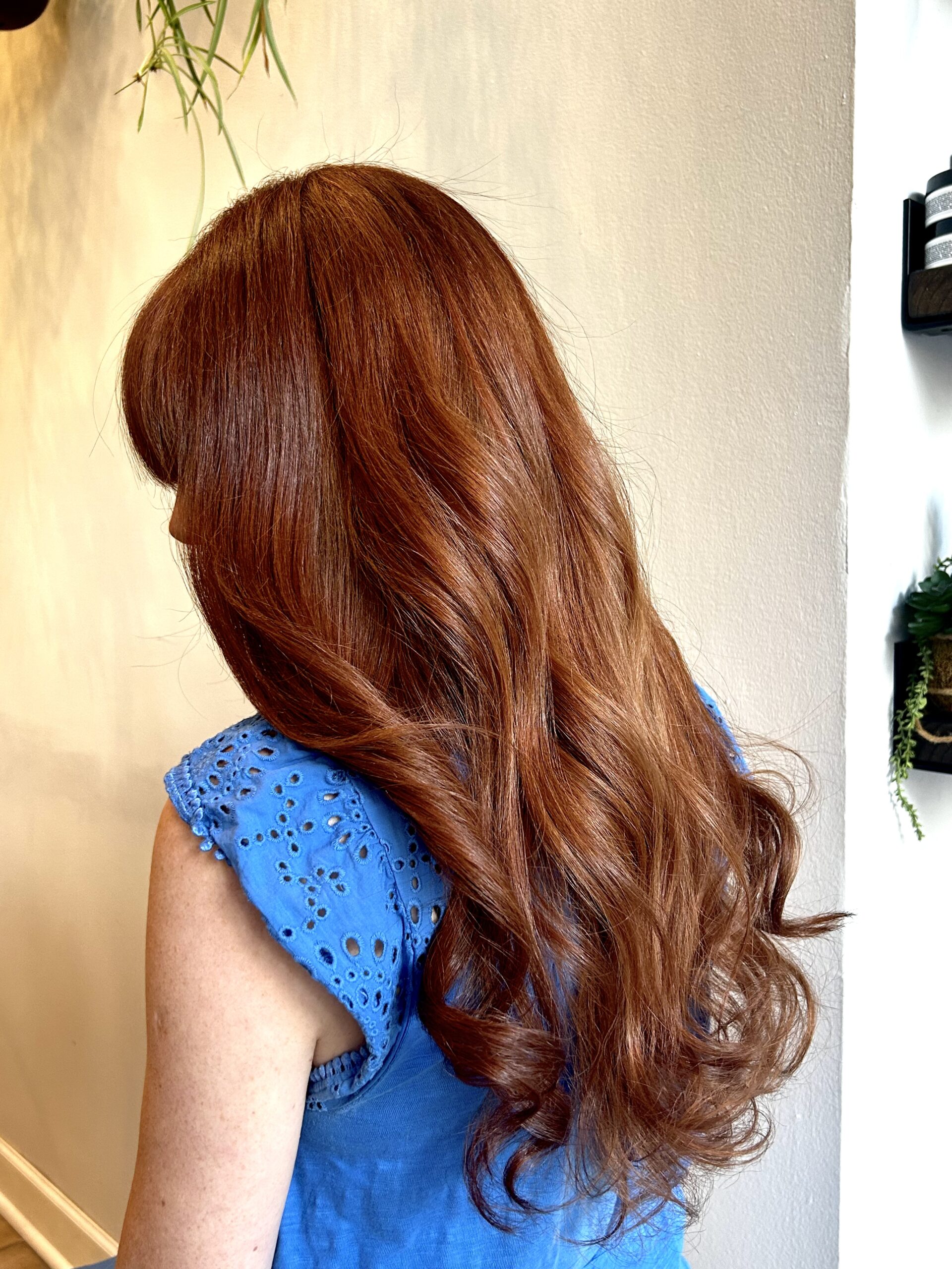 Woman with long, wavy red hair wearing a blue eyelet top.