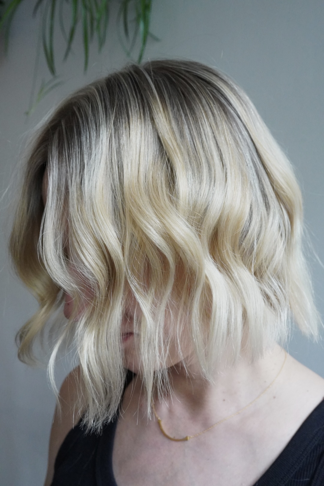 Woman with wavy blonde bob hairstyle and a delicate necklace.