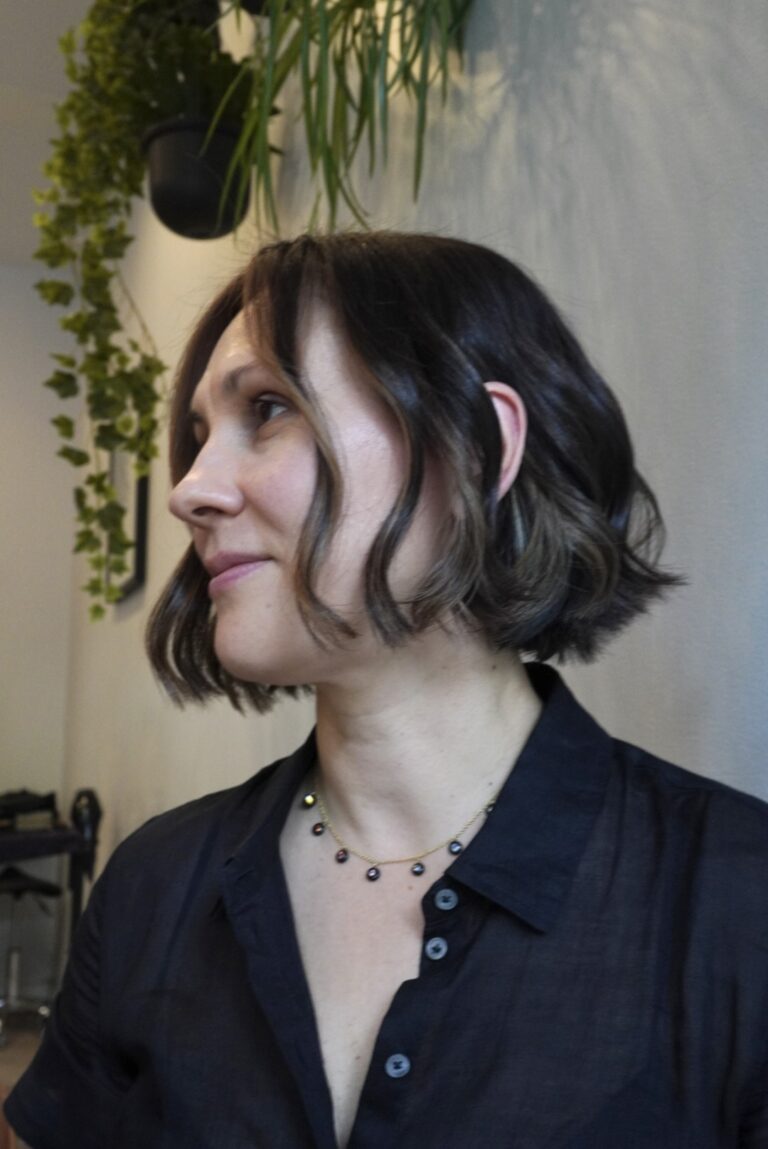 Woman with short wavy hair and a black shirt, facing sideways.