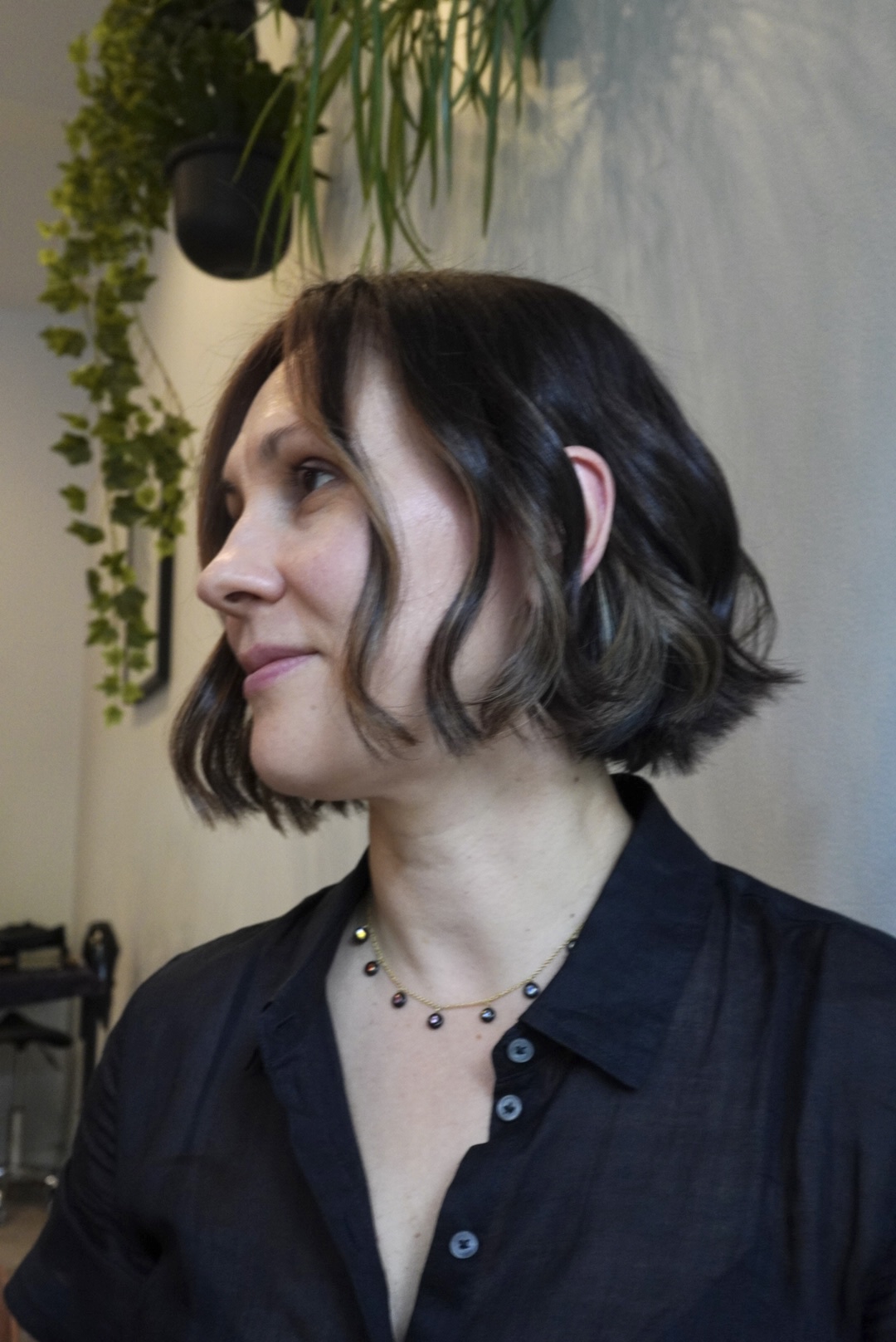 Woman with short wavy hair and a black shirt, facing sideways.