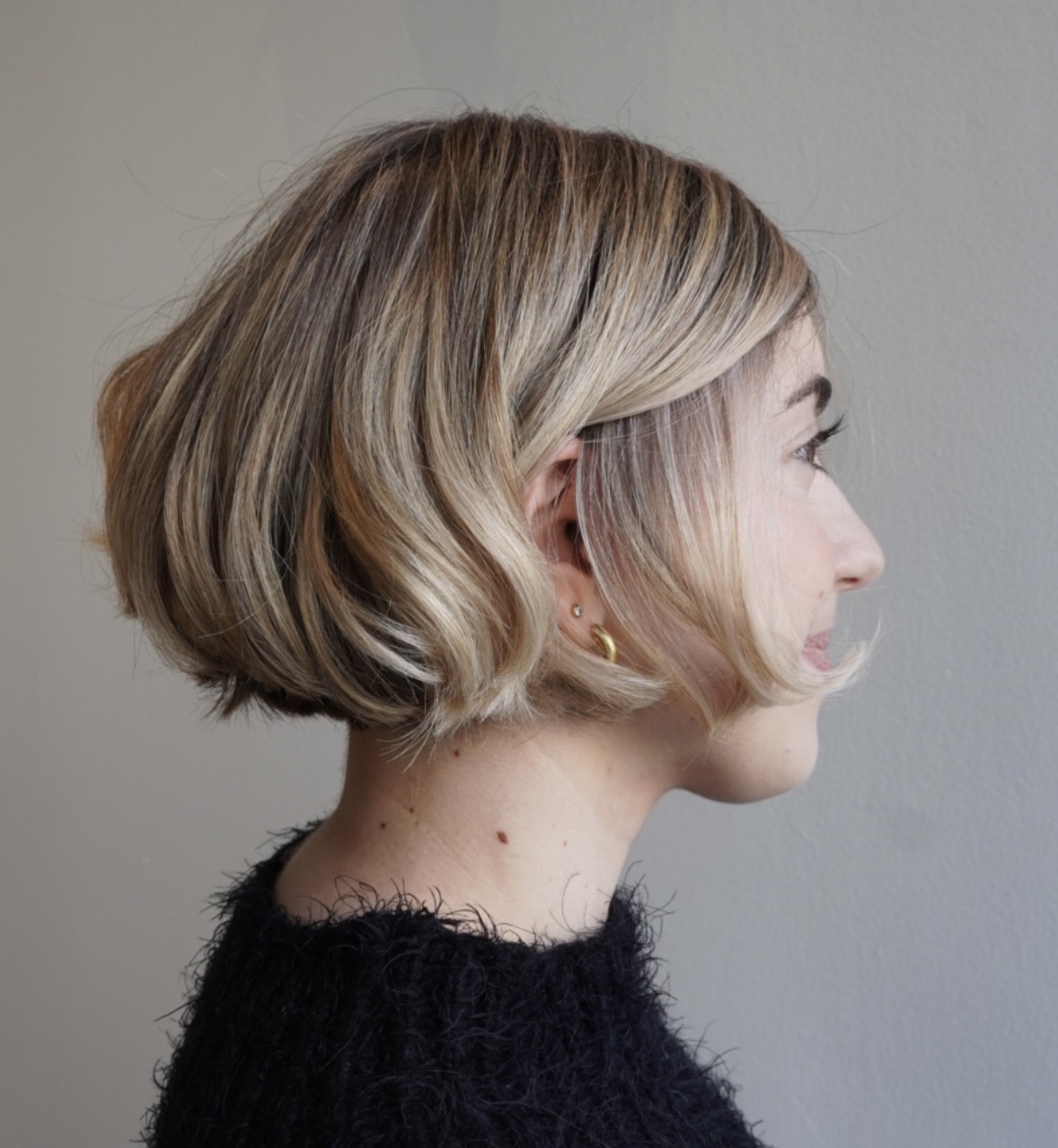 Woman with a short, wavy bob hairstyle, viewed from the side.